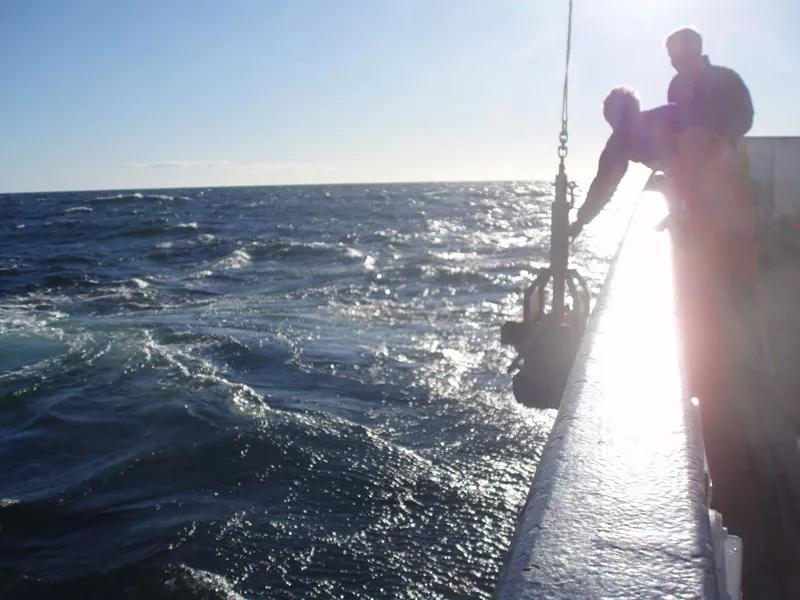 Researchers at sea collectiong water samples.