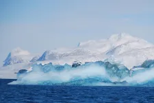 View of sea, sea ice and snow-covered mountains in the background. Greenland.